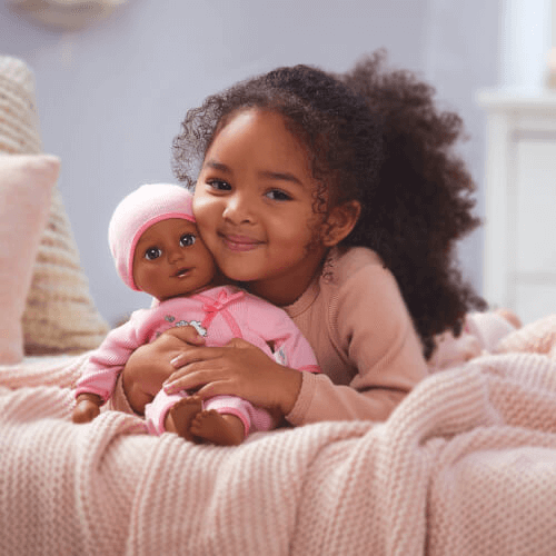 A young girl laying down with her Baby Born baby doll